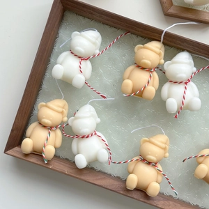 Close-up of cute mini bear candles in cream and khaki colors on a glass tray