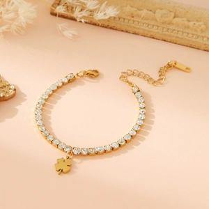 Gold stainless steel bracelet with leaf charm and crystals on soft pink background