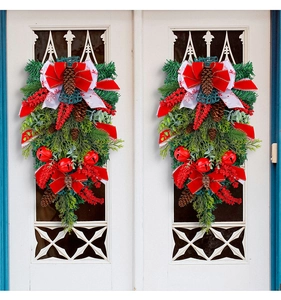 Symmetric Christmas teardrop wreath with pine cones and red bells on white door