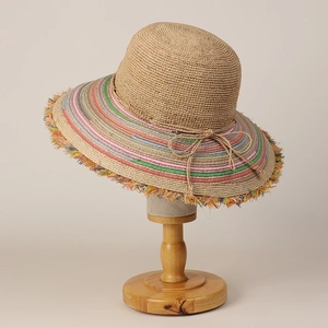Detail of handmade raffia sun hat showing colorful striped brim and frayed fringe edges