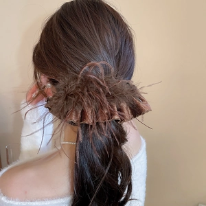 Detail view of brown feather hair clip with shimmery fabric on model back view