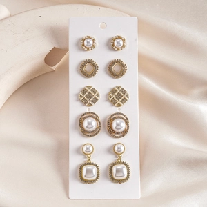 Detail of 6 pairs golden geometric stud earrings with pearls and crystals on card