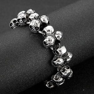 Close-up of vintage steel skull link bracelet with gothic carved details on a black stand