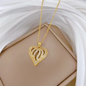 Detail of gold heart pendant with hollow wave lines and sparkling pavé crystals