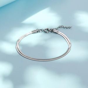 Double-layer silver snake chain bracelet in stainless steel on a light blue background