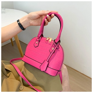Detail of fuchsia crocodile pattern shell bag with golden zipper and rivets