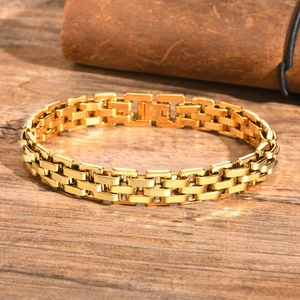 Detailed close-up of golden stainless steel strap bracelet on textured dark wood surface