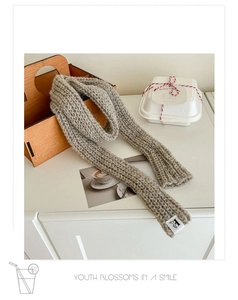 Close-up of fluffy grey wool knit scarf texture with a minimal white woven logo label