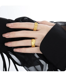 Close-up of golden hollow lace textured diamond ring on hand with elegant black cuff