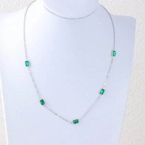 Detail of square emerald green stones on a polished silver stainless steel necklace