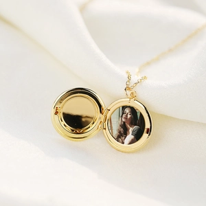 Golden stainless steel round floating locket necklace with photo on white silk background