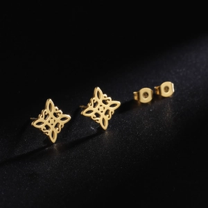 Macro detail of gold stainless steel stud earrings with hollow witch knot pattern