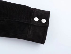 Détail d'une manche en velours côtelé noir avec deux boutons-pression en métal