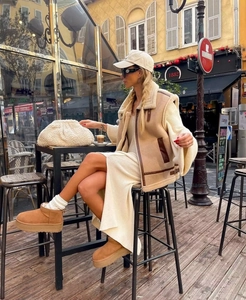Close-up of khaki faux shearling vest with leather trim and beige knit dress outfit