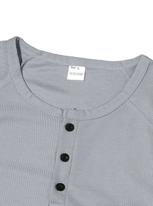 Detailed macro view of the waffle knit texture and buttoned neckline on a gray Henley shirt