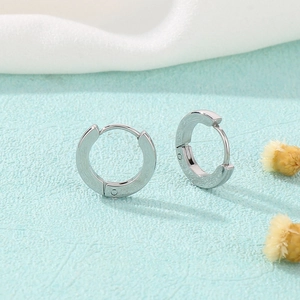 Classic silver stainless steel hoop earrings with polished finish on blue background