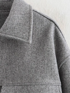 Dettaglio del cappotto di lana grigia che mostra il bavero e la cucitura della spalla