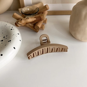 Minimalist matte milk tea hair claw clip on white surface with elegant lifestyle props