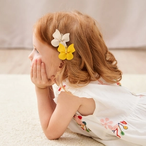 Classic butterfly hair clips in cream and yellow leather, worn by a child model