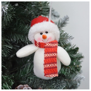 Close-up of plush snowman ornament with red hat hanging on green Christmas tree branches