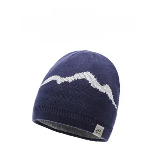 Detail of navy knit beanie with mountain pattern, metal logo tag and thick grey lining