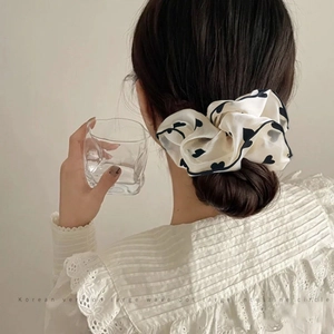 Elegant off-white scrunchie with navy blue hearts on a minimalist bun hairstyle