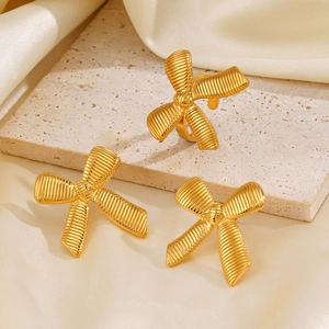 18K gold plated bow earrings set on textured stone with cream silk background