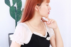 Close-up of a delicate gold square pendant necklace worn by a model in a minimal setting