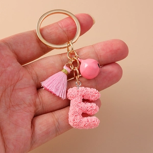 Pink rose petal initial E keychain with tassel and bell on golden metal keyring