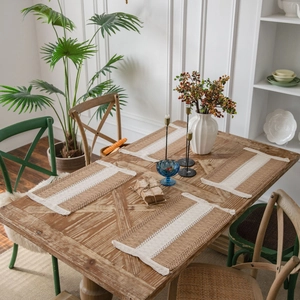 Handwoven rectangular jute placemats with white stripes and fringe on a wooden table