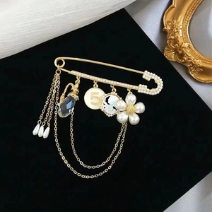 Elegant gold flower brooch with number 5 pendant and pearl tassels on black velvet