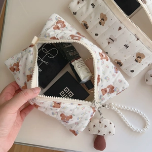 Detail of quilted bear makeup bag with pearl handle and mushroom charm accessory