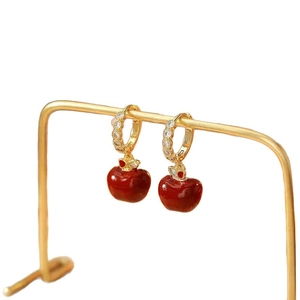 Gold-plated red apple earrings with sparkling cubic zirconia on a minimalist stand