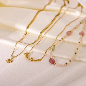 Chic dopamine style beaded necklaces with gold sun and flower pendants on white silk fabric