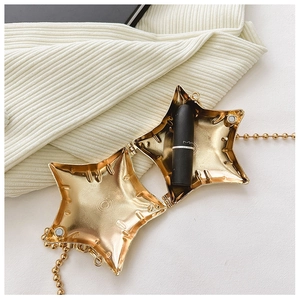 Macro detail of star-shaped gold metal mini bag with magnetic closure and ball chain