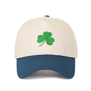Close-up of green clover embroidery on a beige and navy blue two-tone baseball cap