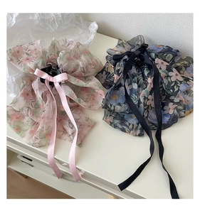 Detailed close-up of floral organza bow hair claws with long ribbon streamers in two colors