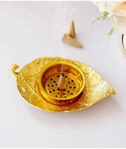 Macro view of golden leaf incense burner with smoke rising from a burning cone