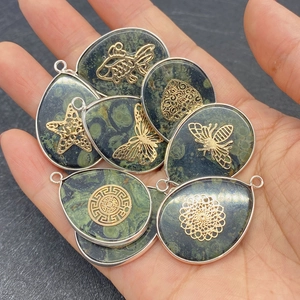 Teardrop green stone pendants with golden tree of life and fish motifs on palm