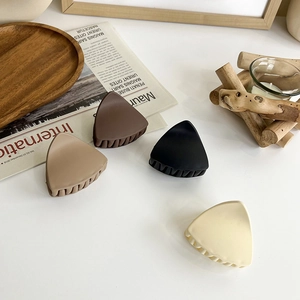 Detail view of matte triangle hair claws in coffee, black, beige, and light brown shades