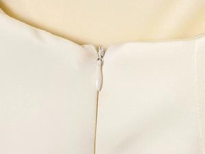 Dettaglio della cerniera invisibile e della trama del tessuto color crema del top
