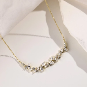 Detail showing wavy gold chain with pear and marquise-cut cubic zirconia on fabric