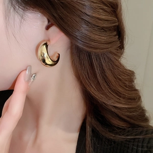 Gros plan d'un mannequin portant une boucle d'oreille en métal doré en forme de C