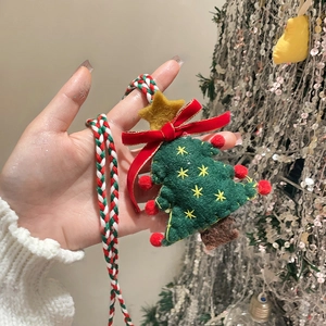 Detail of a green felt Christmas tree pendant with red bow and colorful woven rope
