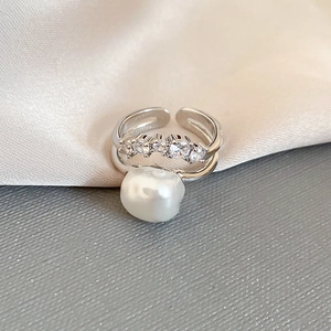 Close-up of irregular baroque pearl ring with four sparkling zircons on double silver band