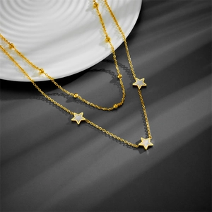 Macro detail of a double-layered gold necklace with star charms and white shell inlay