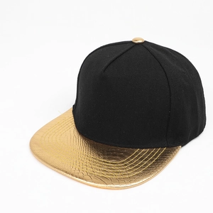 Detail of snapback hat with black fabric crown and gold snakeskin texture flat brim