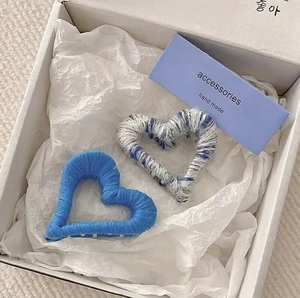Plush heart-shaped hair claw clips in blue and mixed yarn colors inside a gift box