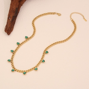 Detail of gold Cuban chain necklace with green heart charms on a premium textured background