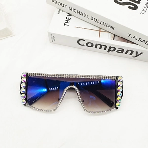 Détail de lunettes de soleil oversize avec strass et verres dégradés bleu et marron